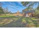 Spacious backyard featuring a brick home, patio area, and mature trees providing ample shade and natural beauty at 1247 Oakcrest Dr, Charleston, SC 29412