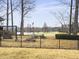 Well-maintained backyard with a black metal fence, mature trees, and partial lake views at 135 Ashley Hill Dr, Goose Creek, SC 29445
