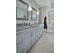 Bright bathroom featuring a long vanity with double sinks, framed mirrors, and travertine tile flooring at 17 Trumbo St, Charleston, SC 29401