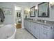 Airy bathroom with double vanity sinks, powder blue cabinets, and soaking tub with an open view to the bedroom at 17 Trumbo St, Charleston, SC 29401
