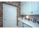 Well-appointed laundry room with a brick wall, white cabinetry, and quartz countertops at 186 N Shelmore Blvd, Mount Pleasant, SC 29464