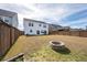Large backyard with a stone fire pit surrounded by grass with a wood fence bordering the yard at 208 Evergreen Ave, Summerville, SC 29485
