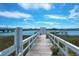Exterior shot of a weathered wooden dock over the water with white railings under a bright blue sky at 2395 Folly Road # 4H, Folly Beach, SC 29439