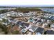 A high-angle shot reveals a residential area with various home styles and a verdant landscape stretching towards a bay at 2942 Clearwater Dr, Mount Pleasant, SC 29466