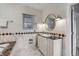 Bright bathroom with a marble countertop vanity, decorative mirror, and accent wall tiling at 40 State St # 1, Charleston, SC 29401