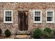 A rustic wooden door with sidelight windows, set in a brick facade at 42 1/2 Hasell St, Charleston, SC 29401