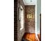 Hallway with rustic brick wall, framed artwork, and hardwood floors leading to a bright doorway at 42 1/2 Hasell St, Charleston, SC 29401