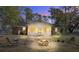 Inviting backyard with a brick house, screened-in porch, and cozy fire pit illuminated at dusk at 425 Ravenwood Rd, Walterboro, SC 29488