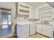 Bright laundry room with washer, dryer, sink, and white cabinets; door to the outside at 425 Ravenwood Rd, Walterboro, SC 29488