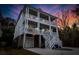 Charming three-story white home with multiple balconies, captured at dusk, with a two-car garage at 530 Amalie Farms Dr, Charleston, SC 29492