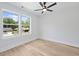 Bright bedroom with wood-look floors, ceiling fan, and double windows offering a clear backyard view at 5806 Beverly Dr, Hanahan, SC 29410