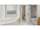 Bathroom featuring a soaking tub with a privacy window and a linen closet at 8153 Governors Walk, North Charleston, SC 29418