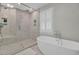 Bathroom features a glass shower with tile surround and soaking tub with shuttered window at 1048 Wharf Indigo Pl, Mount Pleasant, SC 29464