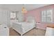 A cozy bedroom with a white bed, stylish pink accent wall and natural lighting at 1048 Wharf Indigo Pl, Mount Pleasant, SC 29464