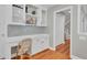 Bright home office with built in shelves and cabinets, desk, wood floors, and view to hallway and stairs at 1048 Wharf Indigo Pl, Mount Pleasant, SC 29464