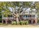 Stunning two-story home featuring a large, mature tree, covered porch, and brick facade with arched openings at 1429 Burningtree Rd, Charleston, SC 29412