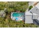 Aerial view of a backyard pool surrounded by lush trees with lounge seating and a sun umbrella on the deck at 1429 Burningtree Rd, Charleston, SC 29412