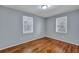A bedroom with hardwood floors, light gray walls, and two windows allowing natural light at 1652 Larry St, North Charleston, SC 29405