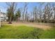 Large backyard enclosed by a wooden fence, featuring expansive trees and partial grass coverage at 1918 Essex Farms Dr, Charleston, SC 29414