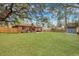Large, grassy backyard with a wooden fence, mature trees, and a shed, perfect for outdoor activities at 201 Maple Dr, Summerville, SC 29485