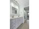 A bathroom with a double sink vanity, decorative mirror, and a door leading to the main bedroom at 2333 Tall Sail Dr # G 607, Charleston, SC 29414
