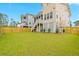 Spacious backyard with green lawn, privacy fence and the rear of the tan and gray two-story house at 325 Blowing Fresh Dr, Charleston, SC 29492