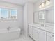 Luxurious all-white bathroom featuring a soaking tub, double windows, and a modern vanity at 325 Blowing Fresh Dr, Charleston, SC 29492