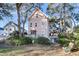 Charming two-story pink home with a front porch nestled among lush trees and greenery at 3271 Johnstowne St, Johns Island, SC 29455