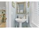 Stylish powder room with a pedestal sink, decorative mirror, and soft blue walls at 3271 Johnstowne St, Johns Island, SC 29455
