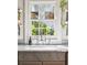 Close-up of kitchen sink with marble counters, open shelves, and views of the greenery outside the window at 36 Bogard St, Charleston, SC 29403