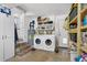 Functional laundry room with washer, dryer, shelving, and steps to an adjacent kitchen with white cabinets at 4437 Logwood Dr, Ladson, SC 29456