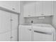 Bright laundry room featuring white cabinetry, a paper towel rack, and modern, front-loading washer and dryer at 4983 Sound View Dr, Mount Pleasant, SC 29466