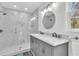Modern bathroom features a large glass shower, double vanity with marble countertop, and large round mirror at 6294 Highway 165, Ravenel, SC 29470