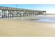 Wooden pier extending over the beach with wet sand in the foreground at 1126 Ocean Blvd # 109116230, Isle of Palms, SC 29451