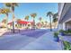 View of street with palm trees, benches, stores with red roofs, and hotel on a sunny day at 1126 Ocean Blvd # 109116230, Isle of Palms, SC 29451