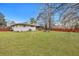 Large grassy backyard enclosed by a wooden fence with a covered porch and mature trees at 1228 Brookside Dr, Hanahan, SC 29410