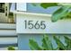 Close-up of house number '1565' beside the entryway stairs, partially obscured by greenery at 1565 Juniper St, Charleston, SC 29407