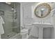 Bright bathroom featuring a glass walk-in shower, pedestal sink with a round wicker mirror, and built-in shelving at 1613 Live Oak Park, Seabrook Island, SC 29455