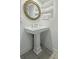 Close-up of the bathroom vanity featuring a pedestal sink with chrome faucet and a round, woven mirror above at 1613 Live Oak Park, Seabrook Island, SC 29455