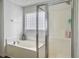 Clean bathroom featuring a soaking tub, glass-enclosed shower, and bright natural light from a privacy window at 1747 Towne St, Johns Island, SC 29455