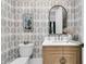 Charming powder room with patterned wallpaper, arch mirror, and light wood vanity at 215 Fell Pt, Daniel Island, SC 29492