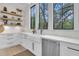 Bright kitchen showcases a farmhouse sink, open shelving, and stainless steel appliances creating a stylish and functional space at 215 Fell Pt, Daniel Island, SC 29492