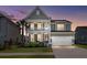 Charming two-story home with a welcoming porch, landscaped yard, and attached two-car garage at dusk at 219 Seaworthy St, Summerville, SC 29486