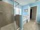 Modern bathroom with a glass shower and a soaking tub, accented by blue walls and natural light at 3072 Adventure Way, Ladson, SC 29456