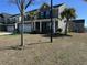 Two-story home with a gray exterior, palm trees, a front porch with white columns, and an attached garage at 3072 Adventure Way, Ladson, SC 29456