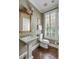 Elegant bathroom featuring a pedestal sink, classic fixtures, hardwood floors, and plantation shutters at 40 New St, Charleston, SC 29401