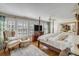 Sunlit primary bedroom featuring a four poster bed, shuttered windows and hardwood floors at 40 New St, Charleston, SC 29401