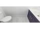 Clean bathroom featuring white marble floors, a toilet and a navy vanity with a white sink at 405 Simmons Ave, Summerville, SC 29483