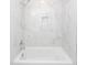 Modern bathtub and shower featuring marble-style tile surround and a built-in niche for toiletries at 405 Simmons Ave, Summerville, SC 29483