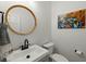 Elegant powder room featuring round mirror, white vanity, black hardware, and tasteful blue crab art at 59 Oyster Point, Charleston, SC 29412